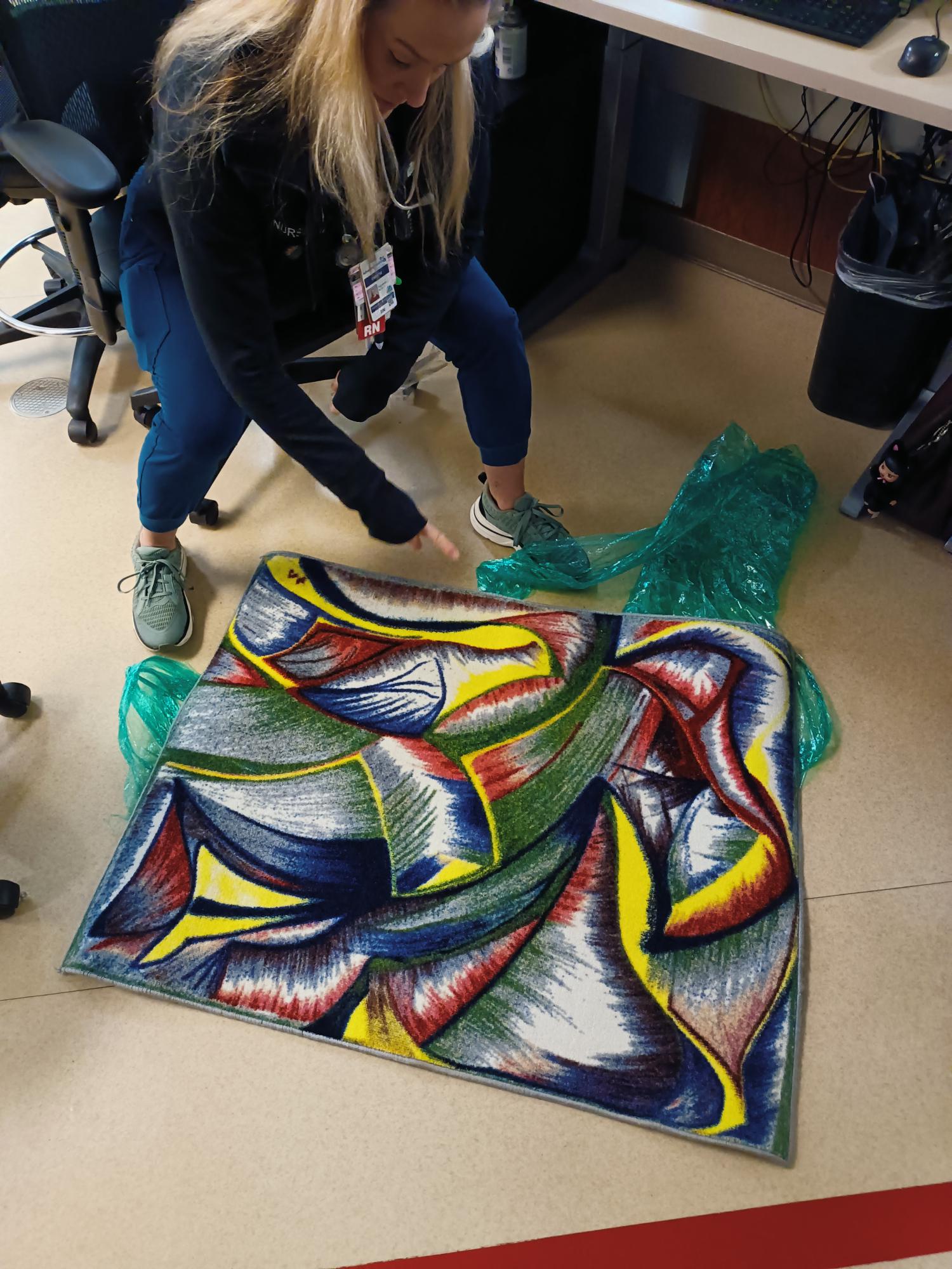 Person unwrapping colorful abstract rug in office
