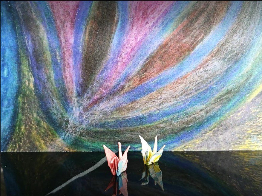Two origami cranes on reflective surface
